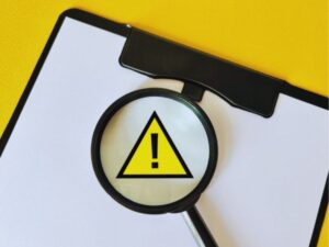 クリップボードと虫眼鏡で見る助成金申請の注意点